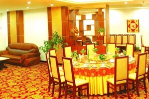 A dining area with a round table, chairs, and a red carpeted floor. - Family Portrait Grand Hotel (Guidong)