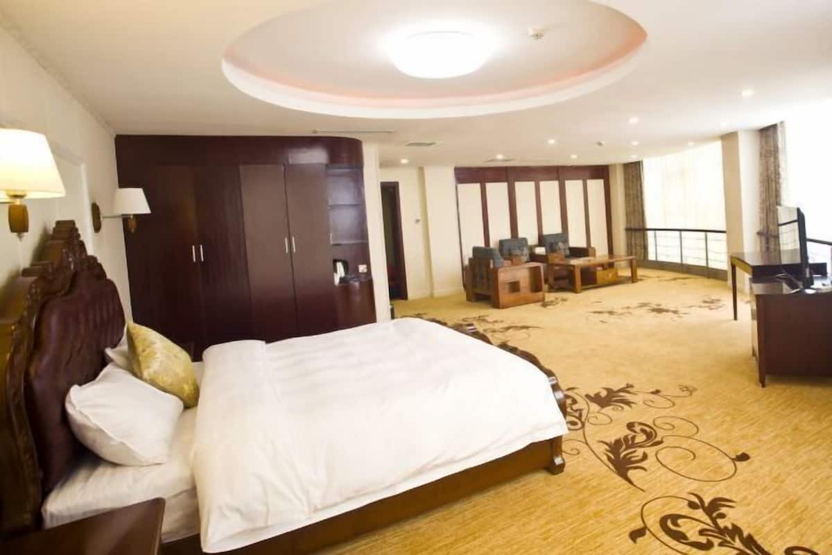A hotel room with a large bed, a desk, and a seating area.