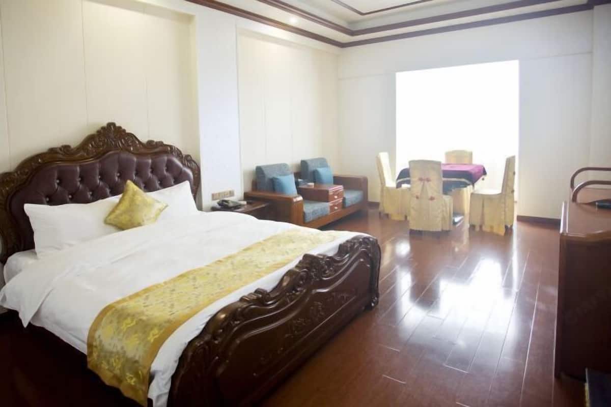 A spacious hotel room with a large bed, a sofa, a chair, and a desk.