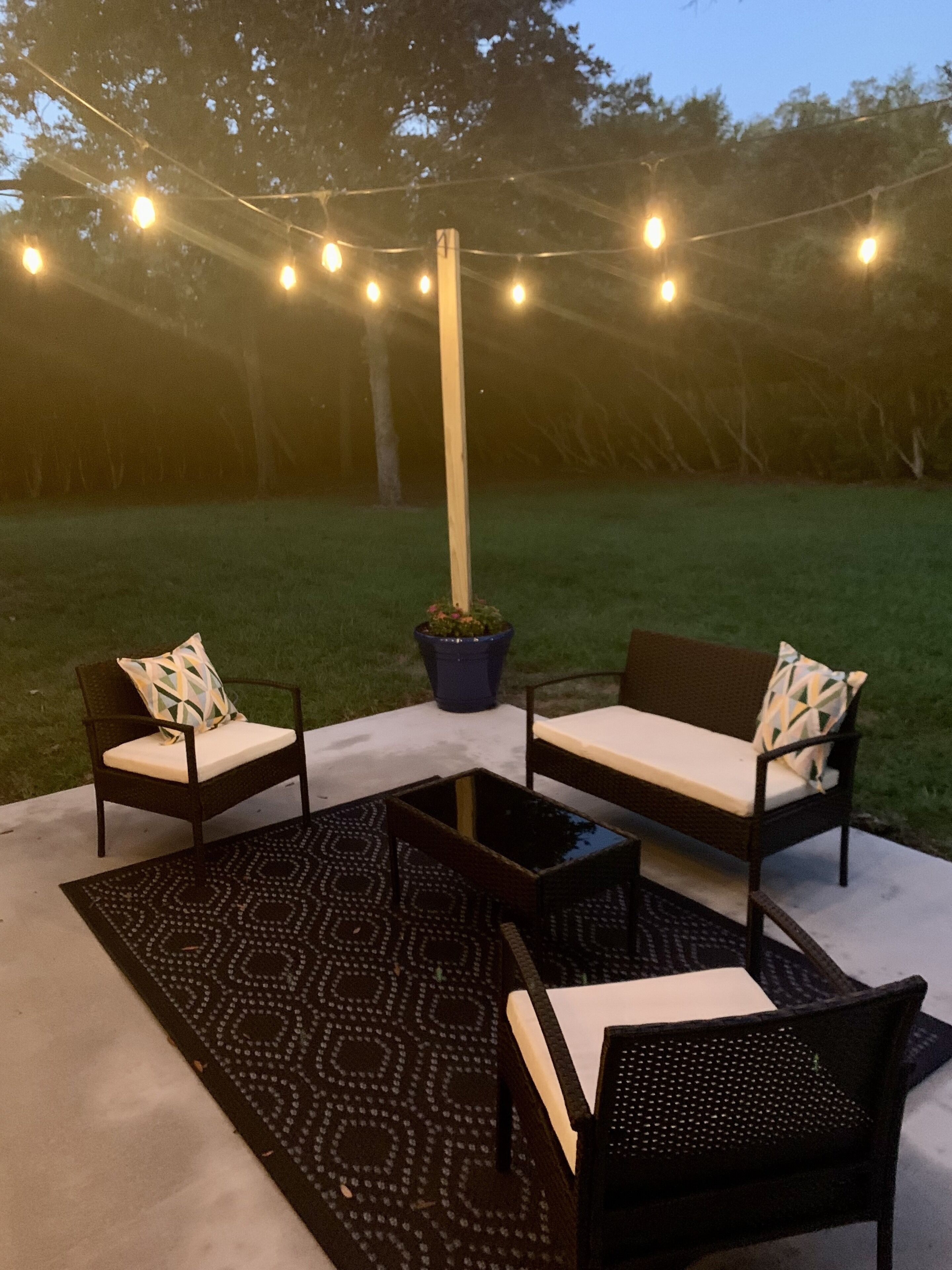An outdoor seating area with two sofas and two chairs, a coffee table, and a patterned rug.