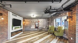 A modern interior with a fireplace, brick walls, and a large TV screen. - Casa Azul Hotel Blu JFK (Queens Village)