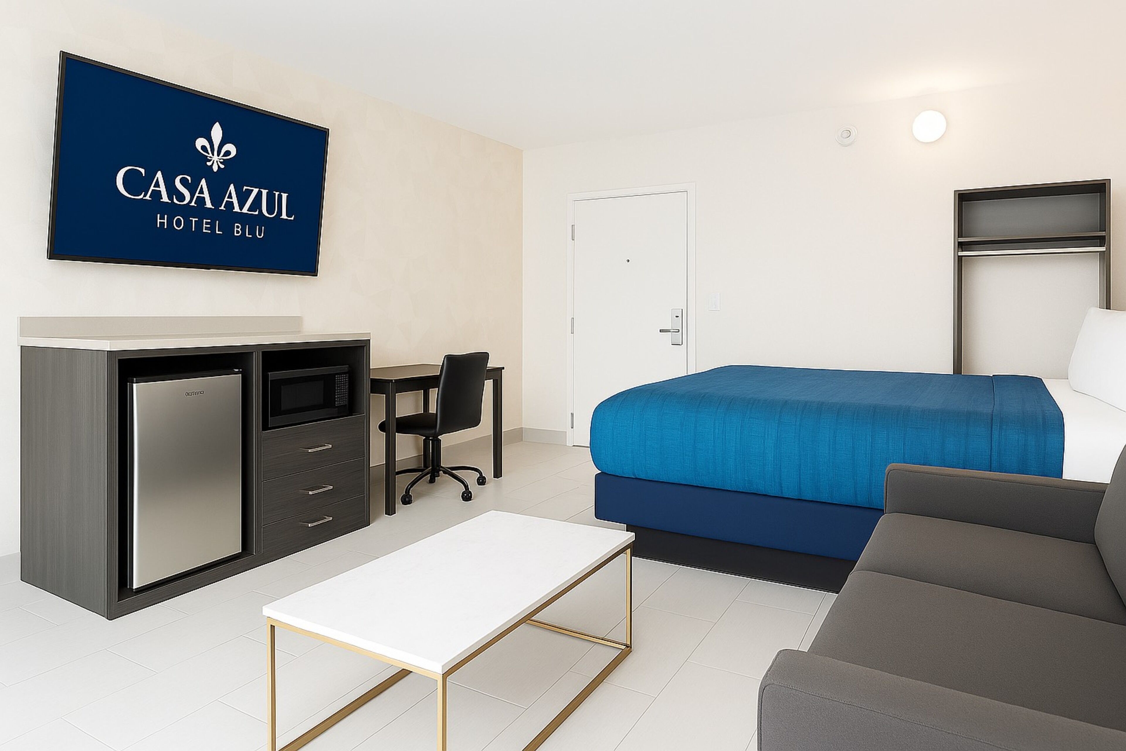 Habitación de hotel con cama, escritorio con computadora, refrigerador y televisión.
