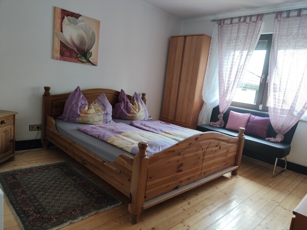 A bedroom with a wooden bed, a nightstand, a wardrobe, and a window with curtains. - VACATION WITH YOUR DOG IN A VACATION HOME WITH A TERRACE, GARDEN, AND POOL (Stegersbach)