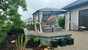 A covered outdoor seating area with a pergola, a sofa, and a lounge chair. - VACATION WITH DOG IN VACATION HOME WITH TERRACE GARDEN AND POOL (Stegersbach)