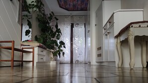 A room with a wooden chair, a white cabinet, a large potted plant, and a patterned curtain. - VACATION WITH DOG IN VACATION HOME WITH TERRACE GARDEN AND POOL (Stegersbach)