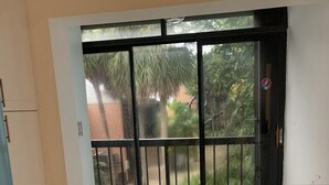 Une cuisine dotée d’une grande porte-fenêtre coulissante donnant sur un balcon, d’un réfrigérateur et d’un plan de travail.