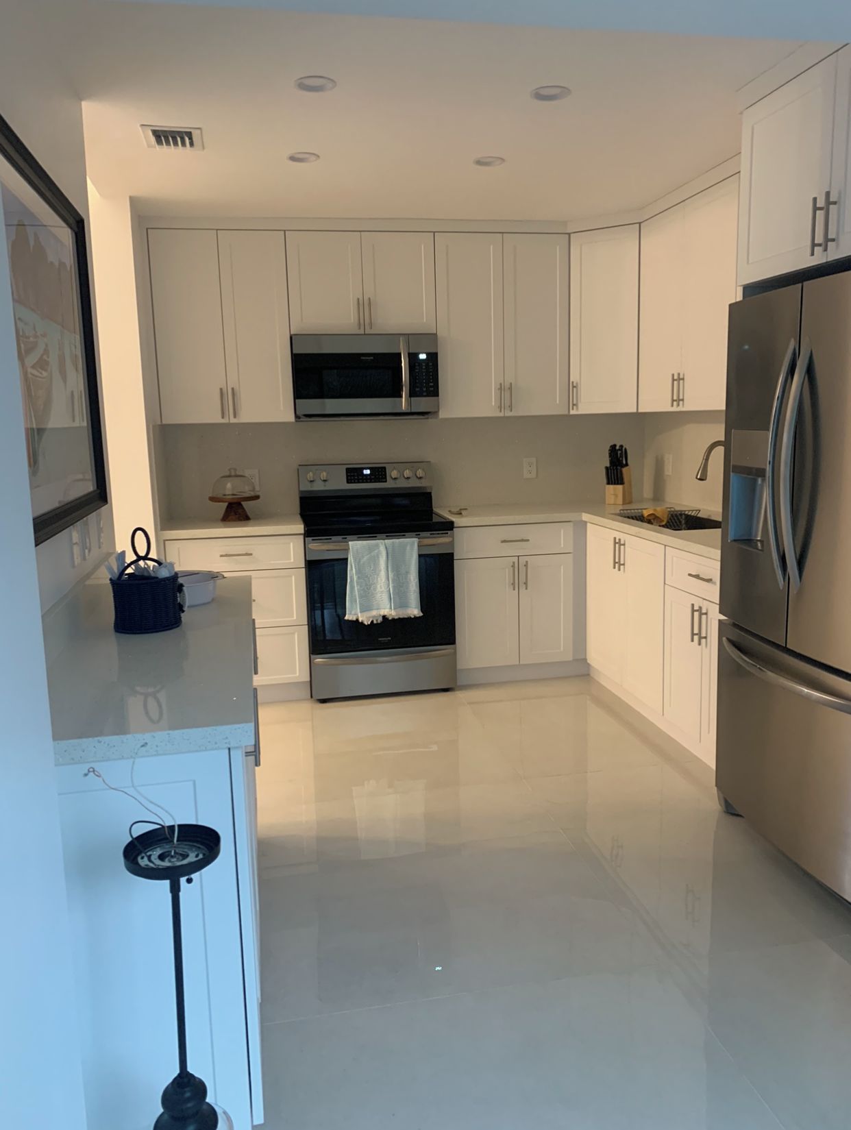 A modern kitchen with white cabinets, stainless steel appliances, and a tiled floor.
