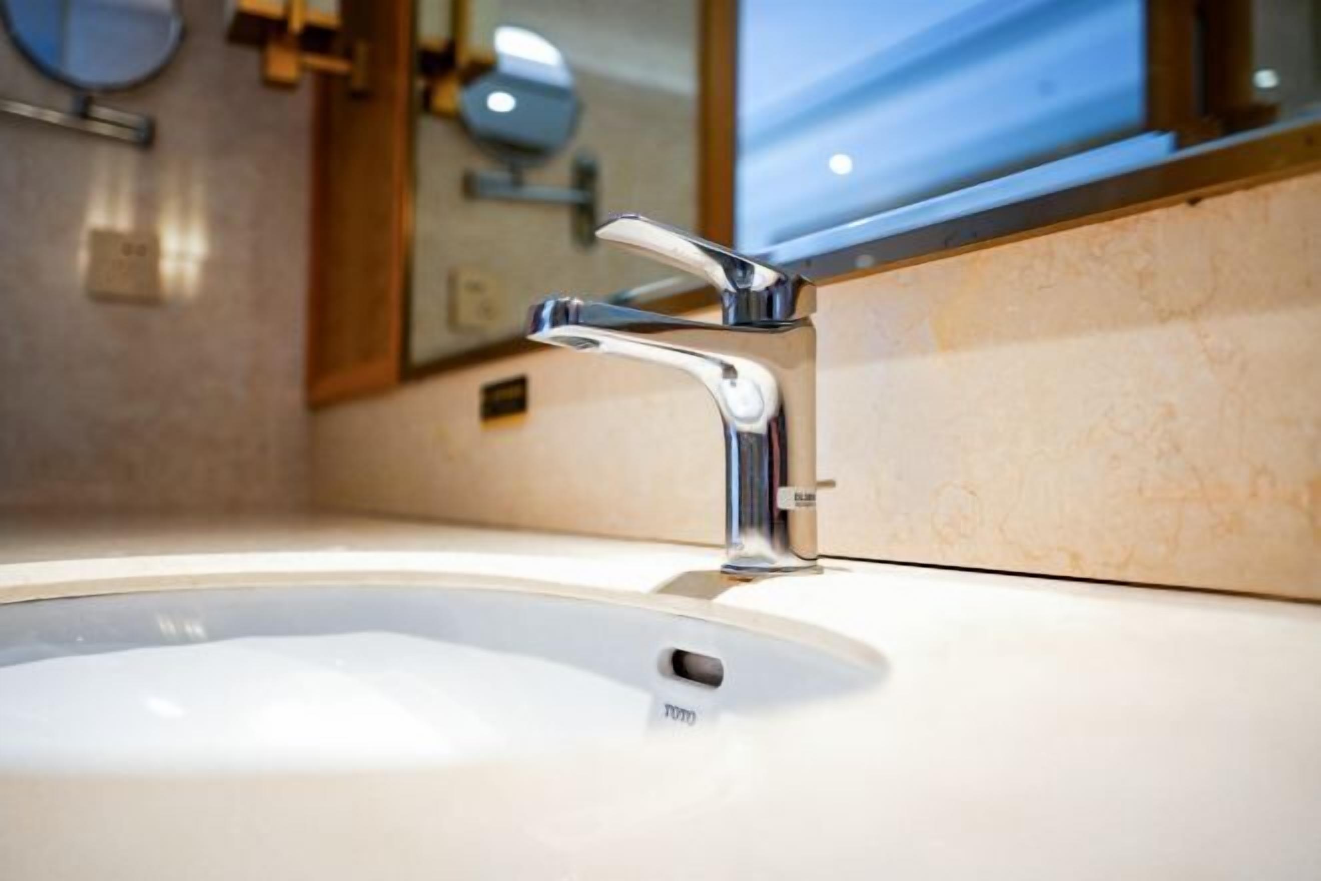Un baño moderno con un lavamanos blanco, grifo cromado y un espejo encima.