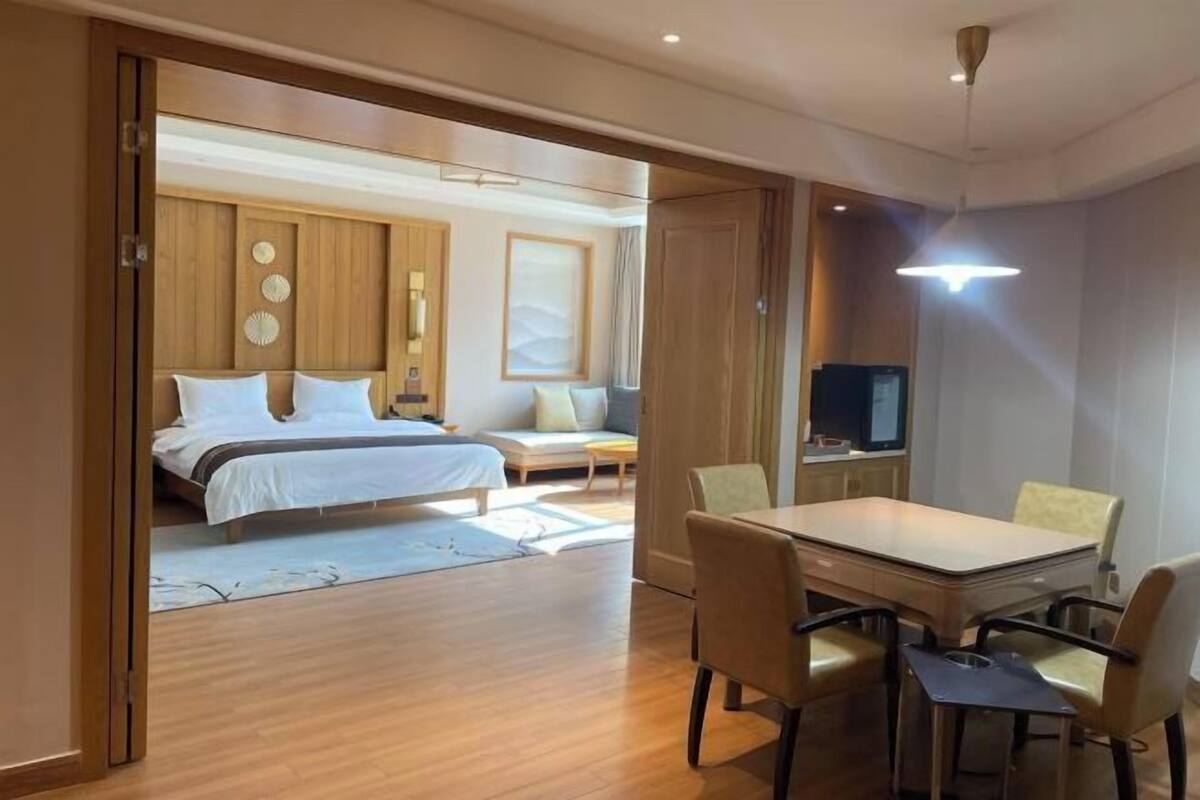 Habitación de hotel con cama, mesita de noche y un área de comedor con sillas y una mesa.