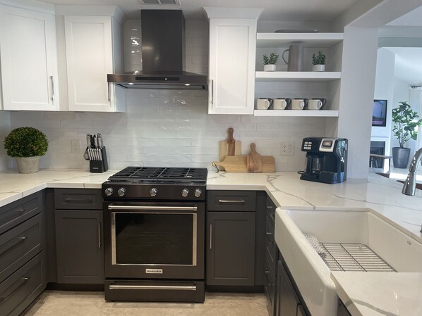 A modern kitchen with black appliances, white cabinetry, and a coffee maker. - Woodhaven CC Luxury home on the Golf Course offering Pickleball, Golf & Tennis (Palm Desert)