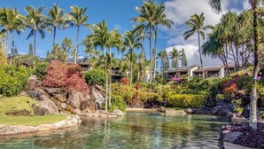 Ein Resort mit einem klaren Pool, umgeben von tropischer Vegetation und Palmen.