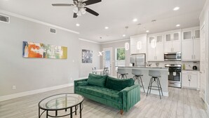 Une cuisine moderne avec des meubles blancs, un coin bar et un canapé en velours vert.