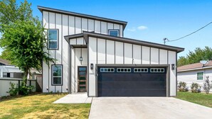 Une maison moderne à deux étages, dotée d’un garage, d’une pelouse bien entretenue et surplombée d’un ciel bleu azur.