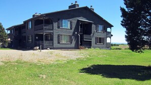 Ein zweigeschossiges Haus mit einem Balkon im zweiten Stock, einer Veranda und einem großen Vorgarten.