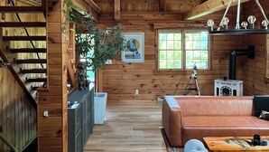 A wooden interior with a staircase, a sofa, a table, and a ceiling fan. - Modern Rustic Log Chalet w/ mtn views, pool & bonus loft on 17 secluded acres  (Grand Gorge)