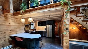 A wooden cabin interior with a kitchen, dining area, and staircase. - Modern Rustic Log Chalet w/ mtn views, pool & bonus loft on 17 secluded acres  (Grand Gorge)