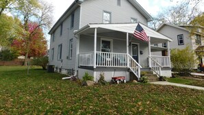 Una casa de dos pisos con un porche y una bandera estadounidense.