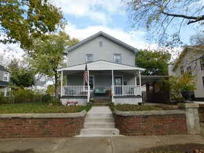 A two-story house with a front porch, a brick wall, and a flag. - Fit For a Crew With A Hot Tub Too-5 bedroom (Pekin)