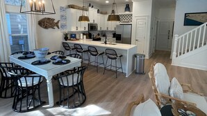 A modern kitchen with white cabinets, a central island, and pendant lighting.