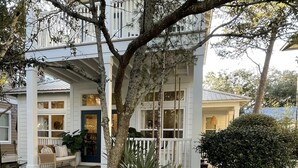 A two-story house with a porch, a white picket fence, and a sign indicating it's for rent by Serenity Now 2.0.