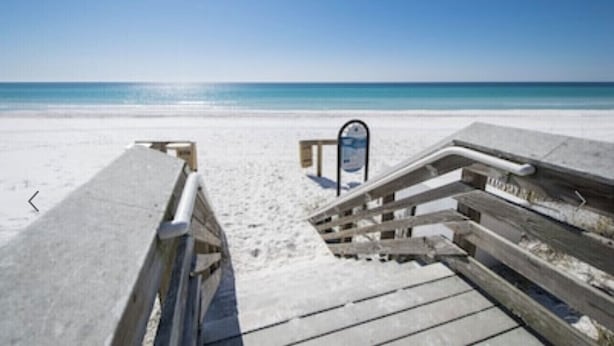 A beach with wooden boardwalks leading to the water.