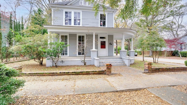 A two-story house with a porch, a front yard, and a driveway.
