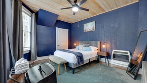 A bedroom with a bed, bedside table, heater, and a ceiling fan.
