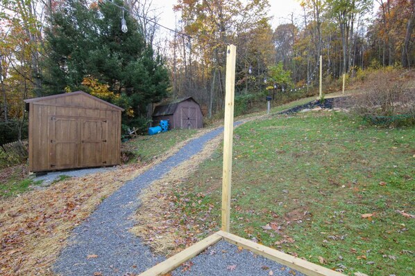 A gravel path leading to a wooden shed in a wooded area.