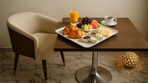 Una mesa con desayuno que incluye croissants, frutas, queso y bebidas.