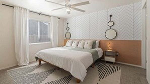 A bedroom with a bed, a ceiling fan, a nightstand, and a wall with circular decorations. - Modern Caldwell Home | Near Freeway & Shopping | Sleeps 10 (Caldwell)