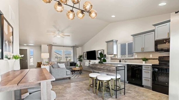 A modern kitchen with a central island, bar stools, and a ceiling fan. - Modern Caldwell Home | Near Freeway & Shopping | Sleeps 10 (Caldwell)