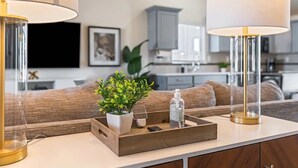 A modern kitchen with a wooden countertop, a potted plant, and a tray with a bottle and a remote control. - Modern Caldwell Home | Near Freeway & Shopping | Sleeps 10 (Caldwell)
