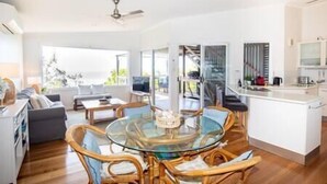 A modern kitchen with a glass dining table, wooden chairs, and a view of the outdoors.
