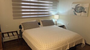 Une chambre à coucher avec un lit, une table de chevet, une lampe et une fenêtre avec des stores.