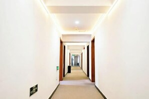 A hotel hallway with a carpeted floor, wooden doors, and a light fixture on the ceiling. - Lutong Hotel (Hohhot)