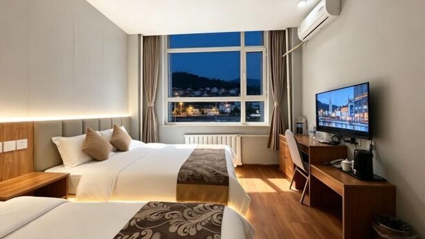 Habitación de hotel con dos camas, un escritorio, un televisor y una ventana con vista a la ciudad.
