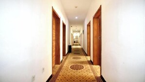 Un largo y estrecho pasillo de hotel con puertas de madera a ambos lados y alfombra estampada.