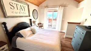 Une chambre à coucher avec un lit, une commode, une chaise, un bureau, une lampe et une pancarte sur laquelle est écrit : « RESTEZ un peu ».