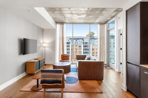 Una sala de estar moderna con un televisor de pantalla plana, un sofá, una mesa de centro y una mesa de comedor.