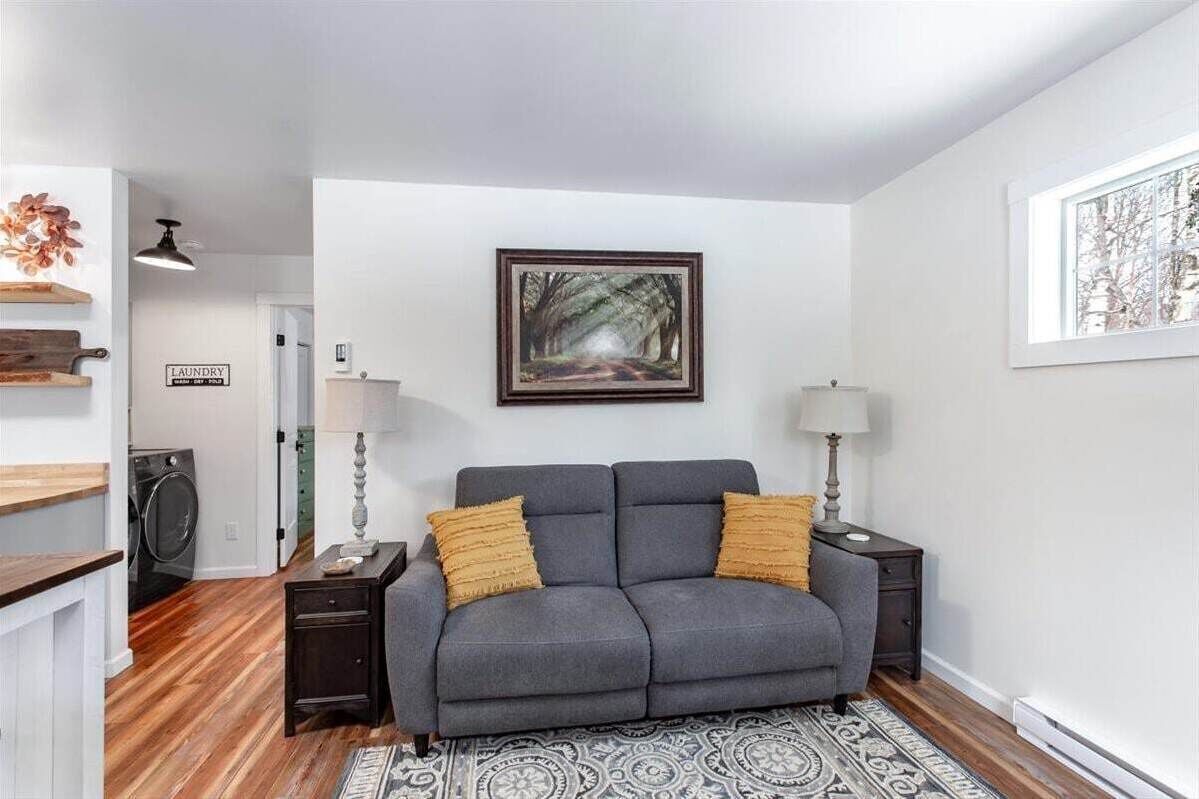 A living room with a gray sofa, two side tables with lamps, a framed picture on the wall, and a rug on the floor.