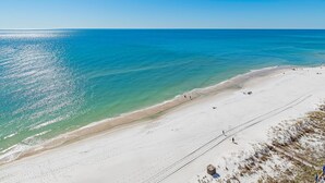 Una playa con agua turquesa cristalina, una orilla de arena y una pasarela de madera que conduce al agua.