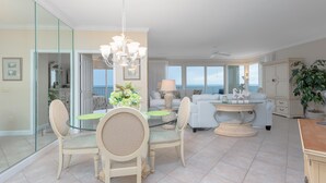 Amplia sala de estar con comedor de vidrio, un candelabro y vistas al océano.