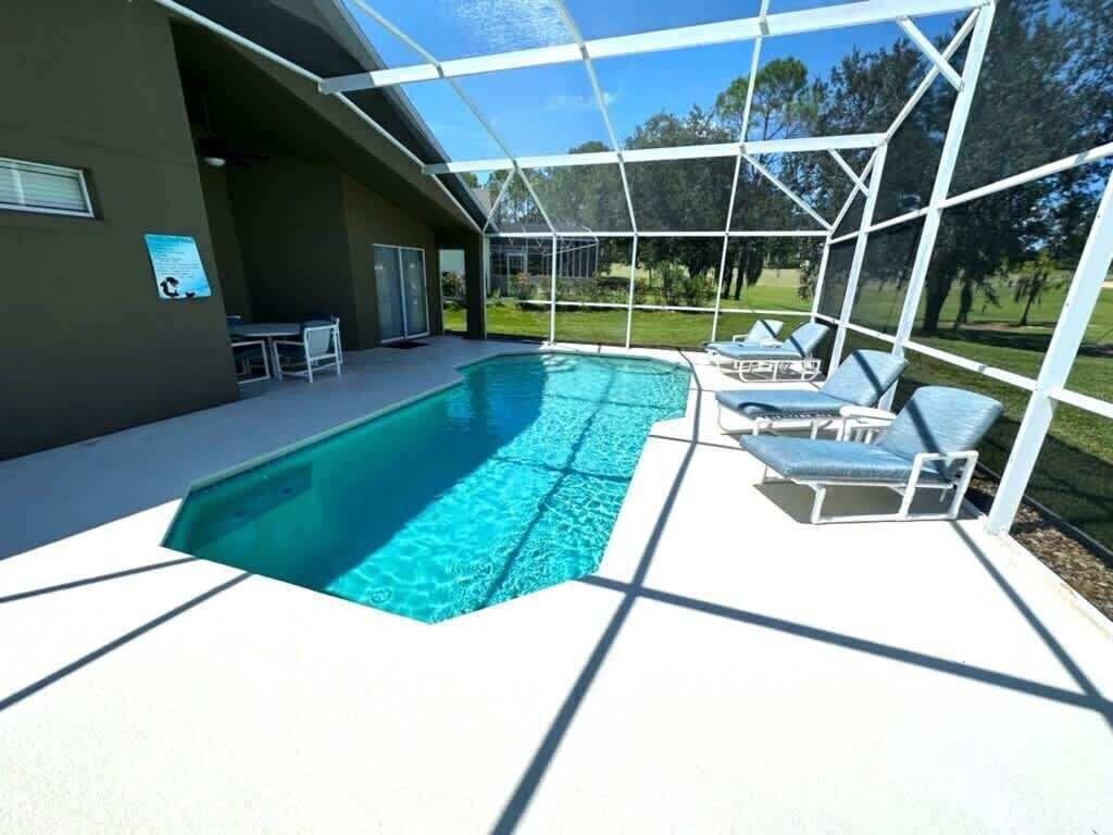 A covered swimming pool with lounge chairs and a patio area.