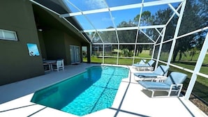 Une piscine couverte avec des chaises longues et un espace patio.
