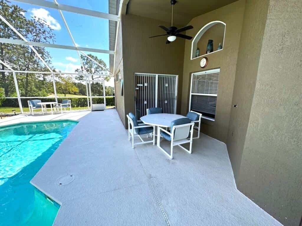 Ein überdachter Patio-Bereich mit Pool, Gartenmöbeln und Deckenventilator.