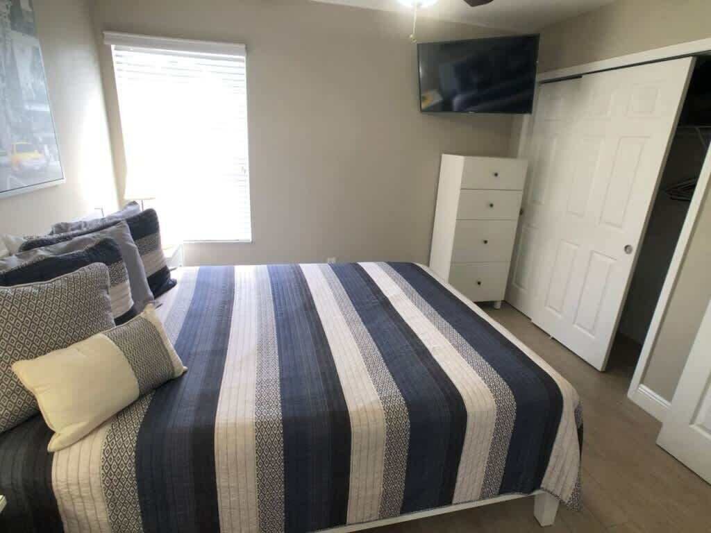 A bedroom with a bed, a dresser, a TV, and a closet.