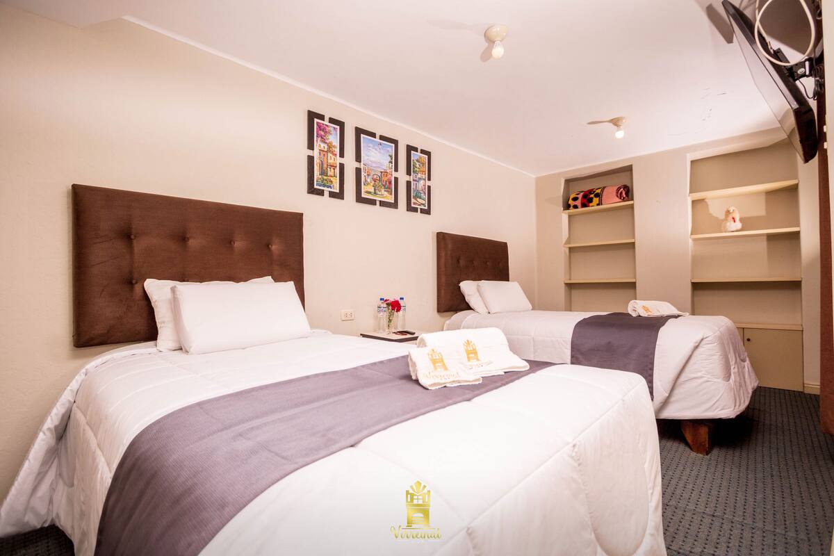 A hotel room with two beds, a nightstand, a shelf with toiletries, and a ceiling fan.