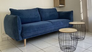 A blue sofa, two wire coffee tables, a wooden shelf with decorative items, and a wall clock. - Pretty little house 100m from the beach and shops, with WIFI connection (Bretignolles-sur-Mer)
