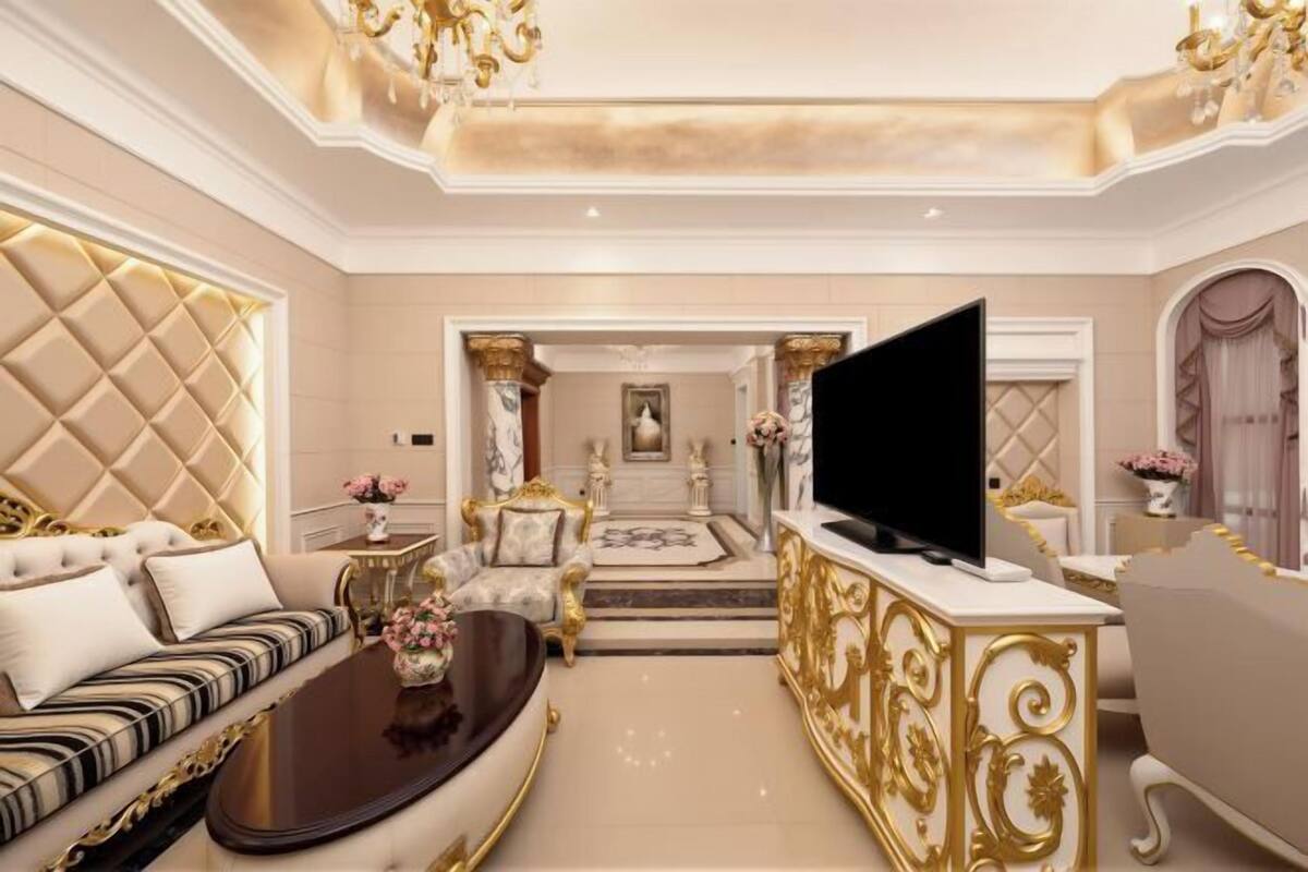 A luxurious living room with a sofa, a coffee table, a TV, and a decorative fireplace.