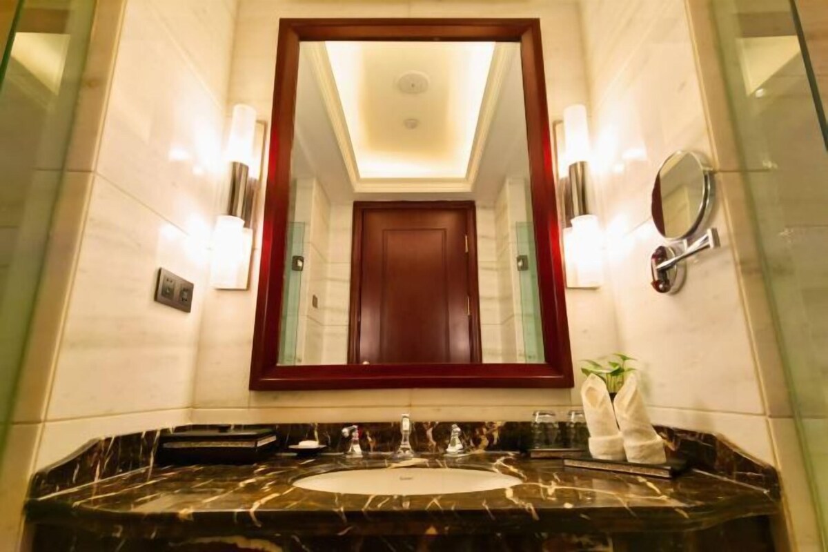 A bathroom with a large mirror, a marble sink, and a wooden door.